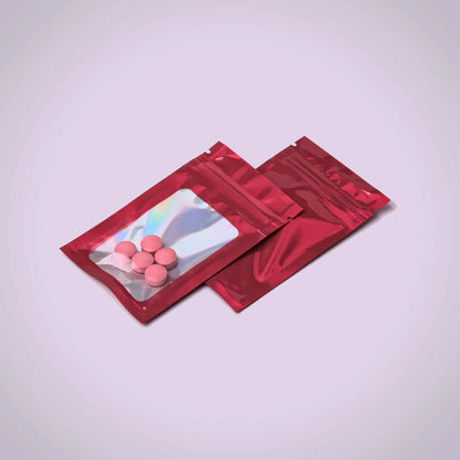 Two red transparent pouches with pink and white 7ohBLACK 7-oh tablets on a light gray background